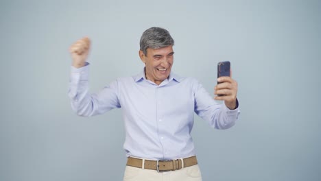 The-old-man-looking-at-the-phone-is-happy.